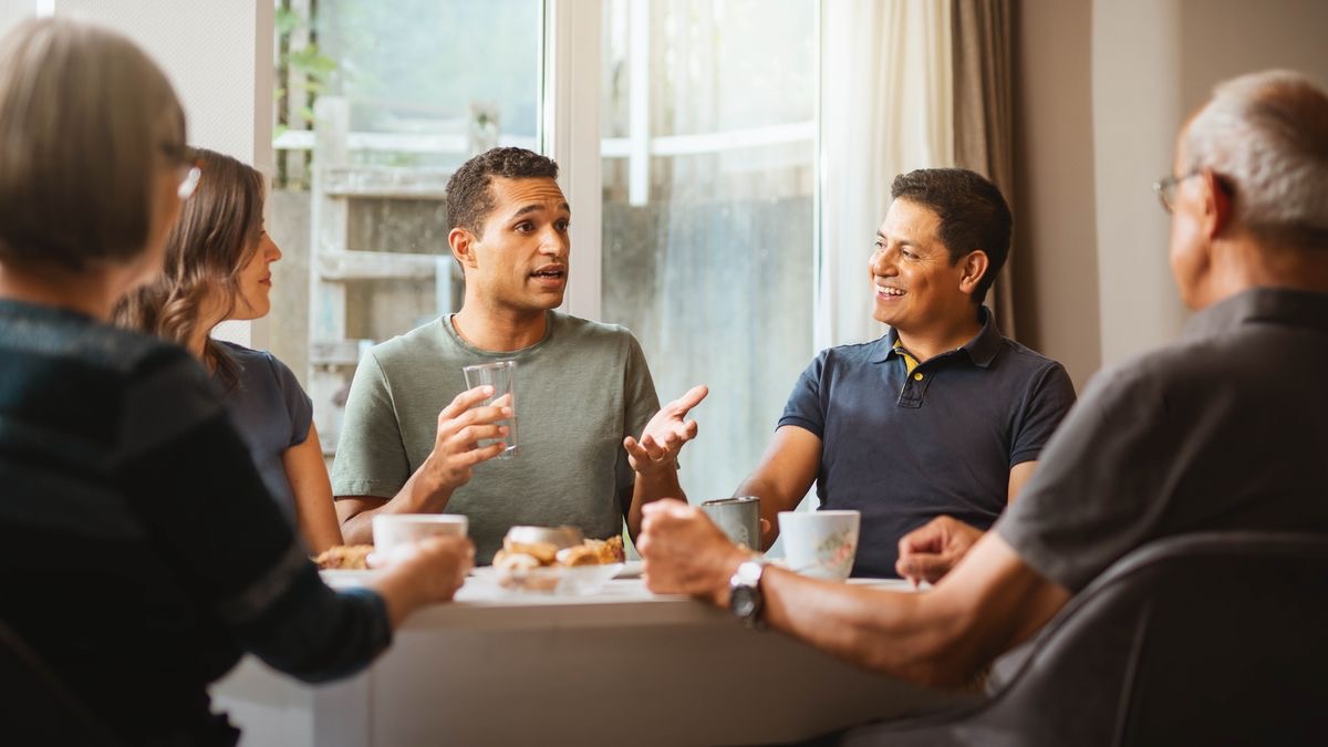 Un grupito de hermanos comiendo juntos. Uno de ellos está hablando y los demás lo escuchan con atención.
