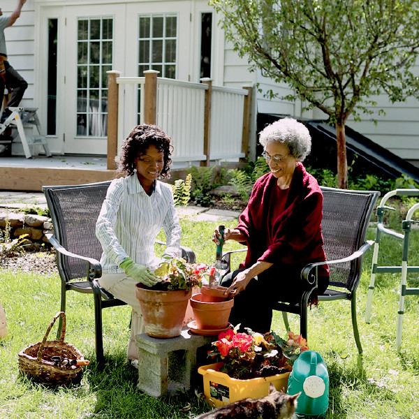 A younger sister helps an older sister plant some flowers