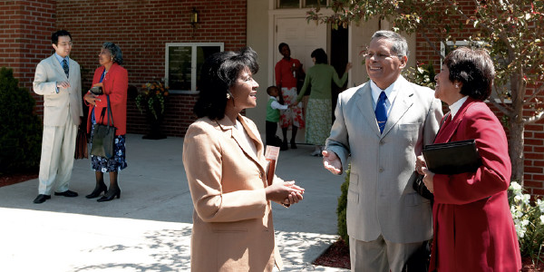 Jehovah’s Witnesses visit with one another outside a Kingdom Hall
