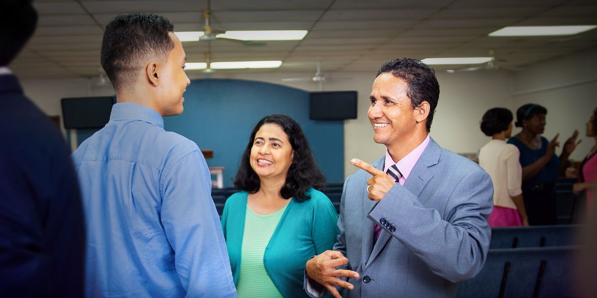 Mario Antúnez, with his wife Patricia by his side, using Honduras Sign Language (LESHO) to communicate with a young man at the Kingdom Hall.