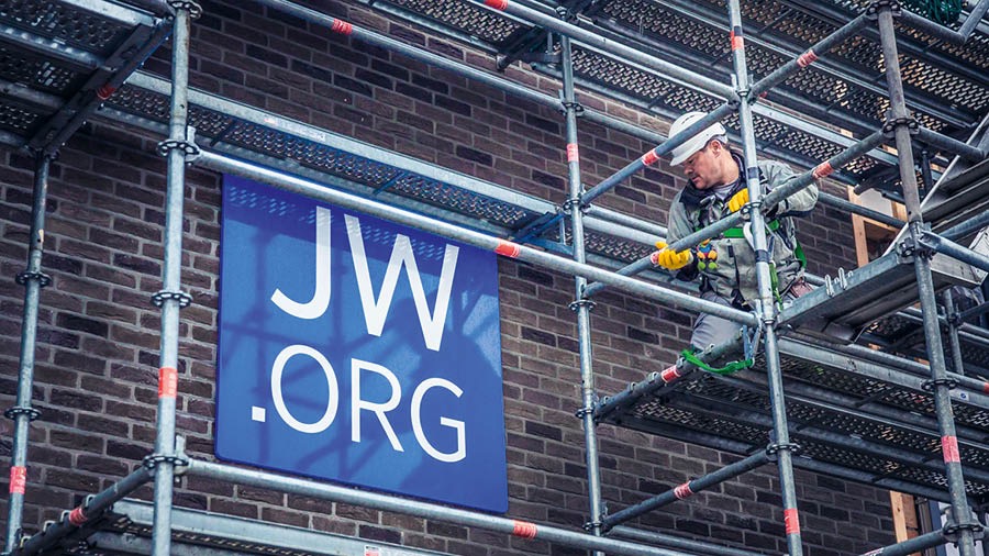 A Witness setting up scaffolding outside a building used for worship.