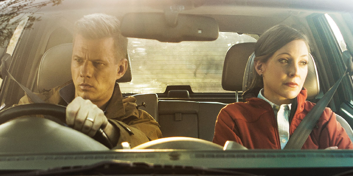 A husband and wife angrily stare out the windows of a car