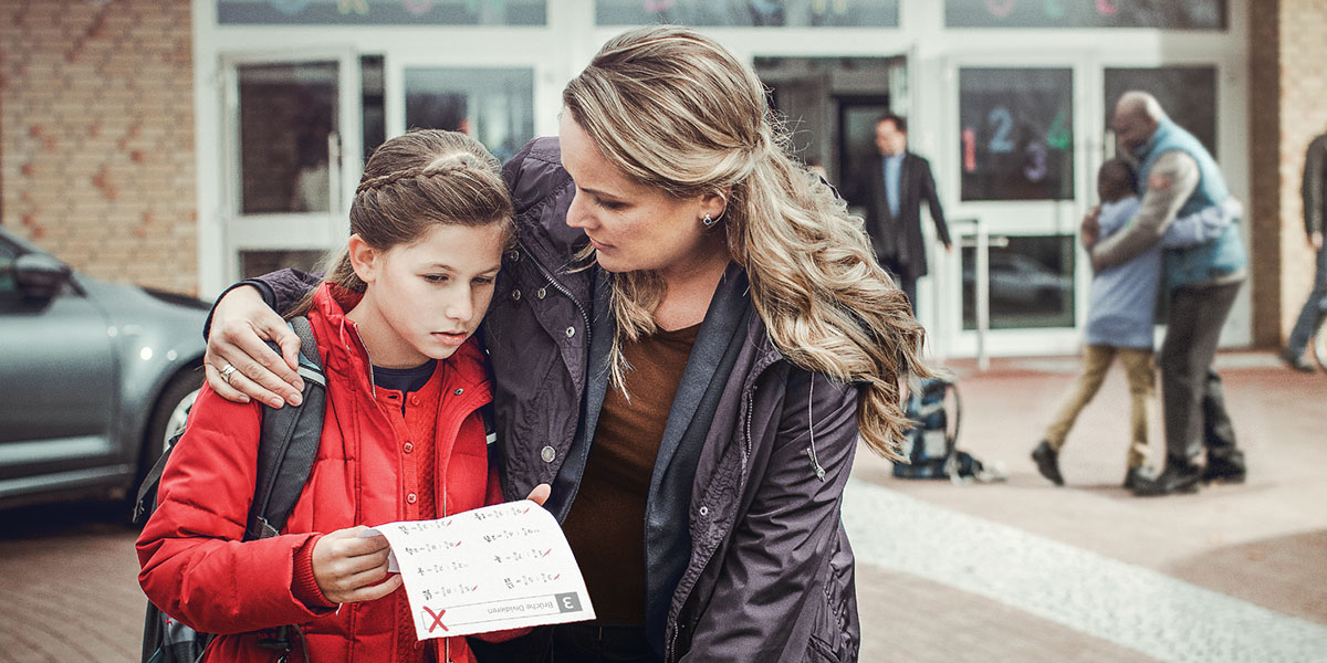 A mother comforts her daughter who received a poor grade on a school paper