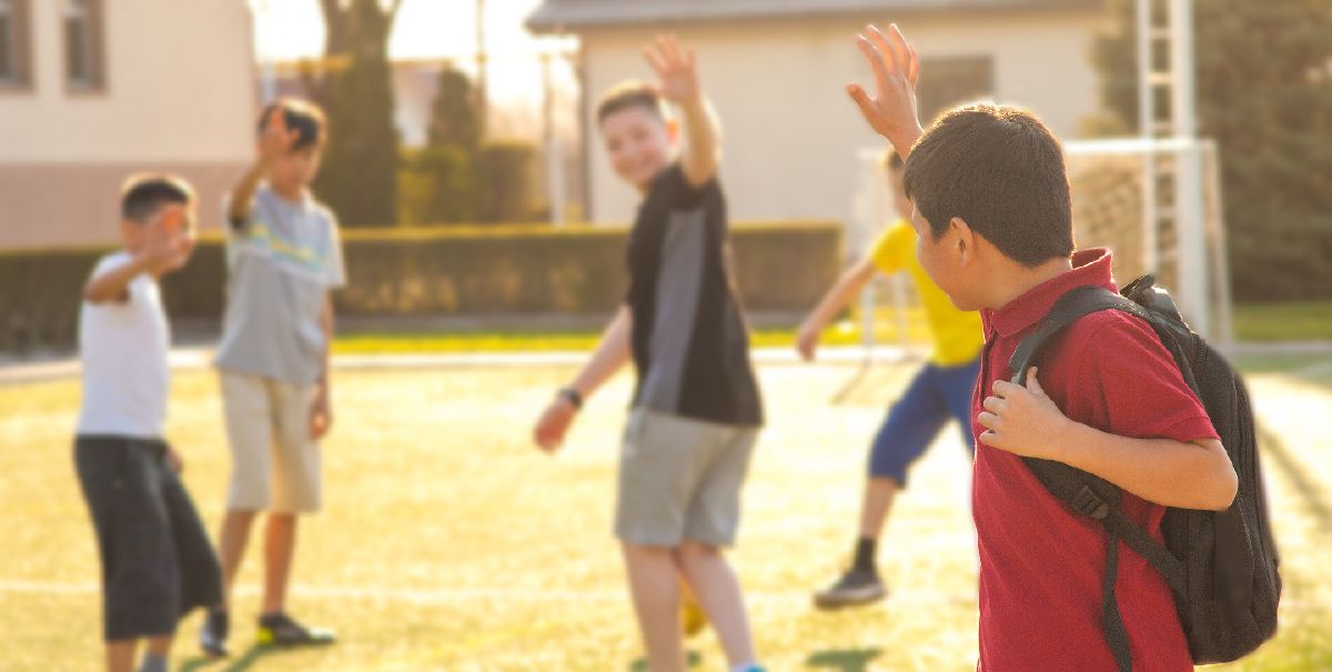A boy waves goodbye to his school friends