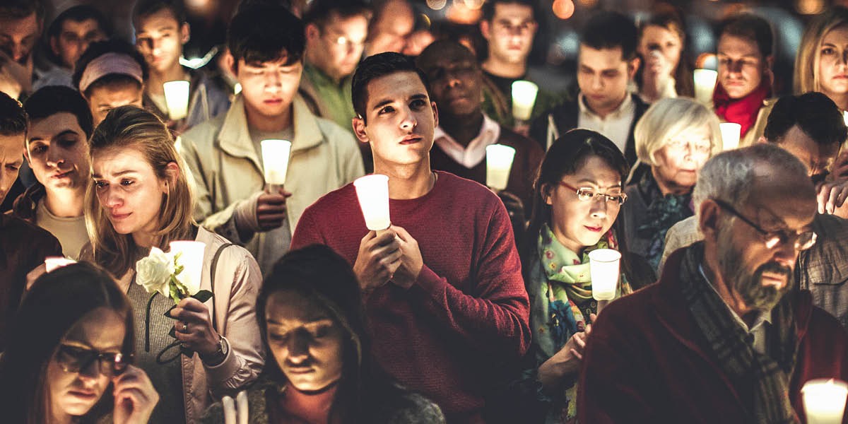 Grieving people hold candles