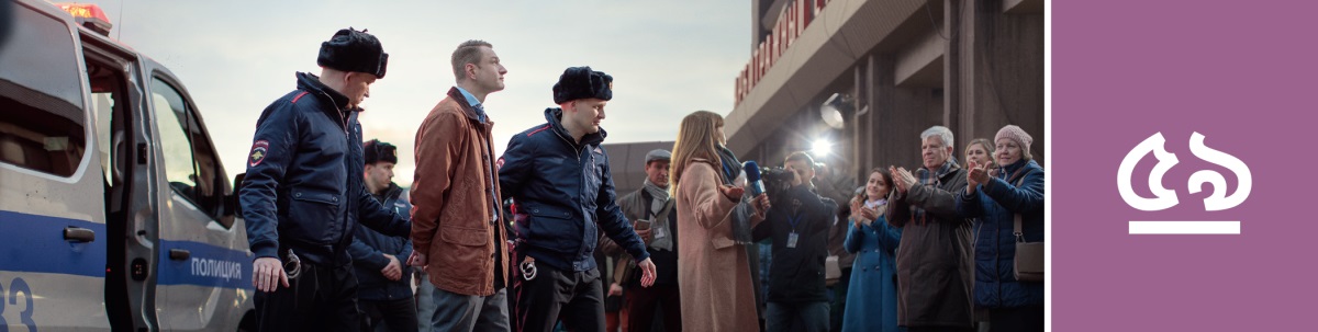 পাঠ ৫৯. দু-জন অফিসার একজন সাক্ষি ভাইকে হাতকড়া পরিয়ে নিয়ে যাচ্ছেন আর সাংবাদিক ও সহসাক্ষিরা রয়েছে।