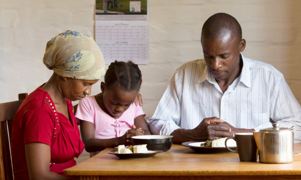 সাধারণ খাবারের জন্য ঈশ্বরকে ধন্যবাদ দিয়ে একজন ব্যক্তি তার ত্রী ও মেয়ের সগ পার্থনা করছন