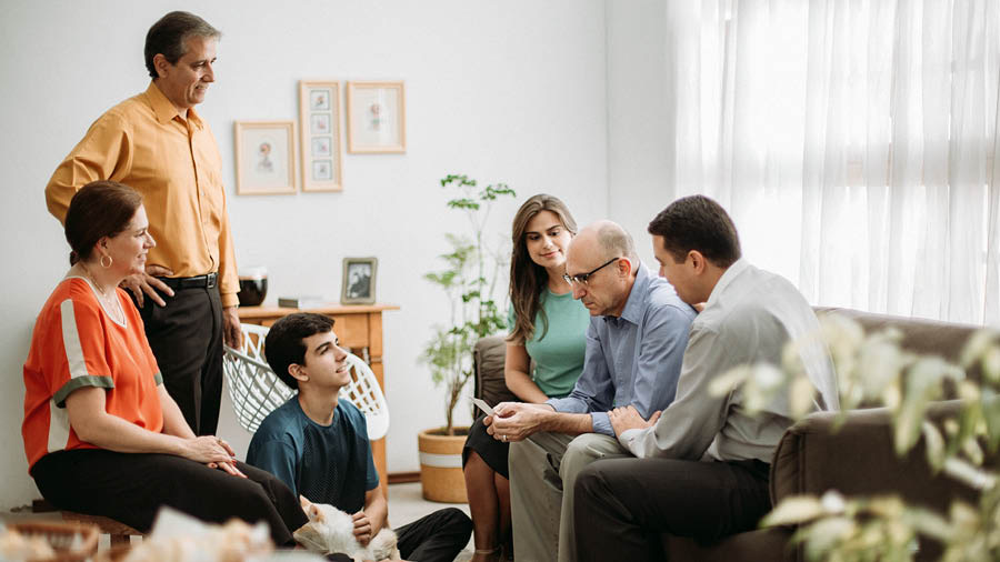 একজন শোকাহত ব্যক্তি একটা ফোটো ধরে আছেন আর তার কিছু বন্ধুরা তাকে সান্ত্বনা দিচ্ছে।