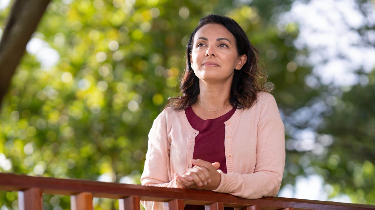 Una germana meditant a l’aire lliure recolzada en una barana.