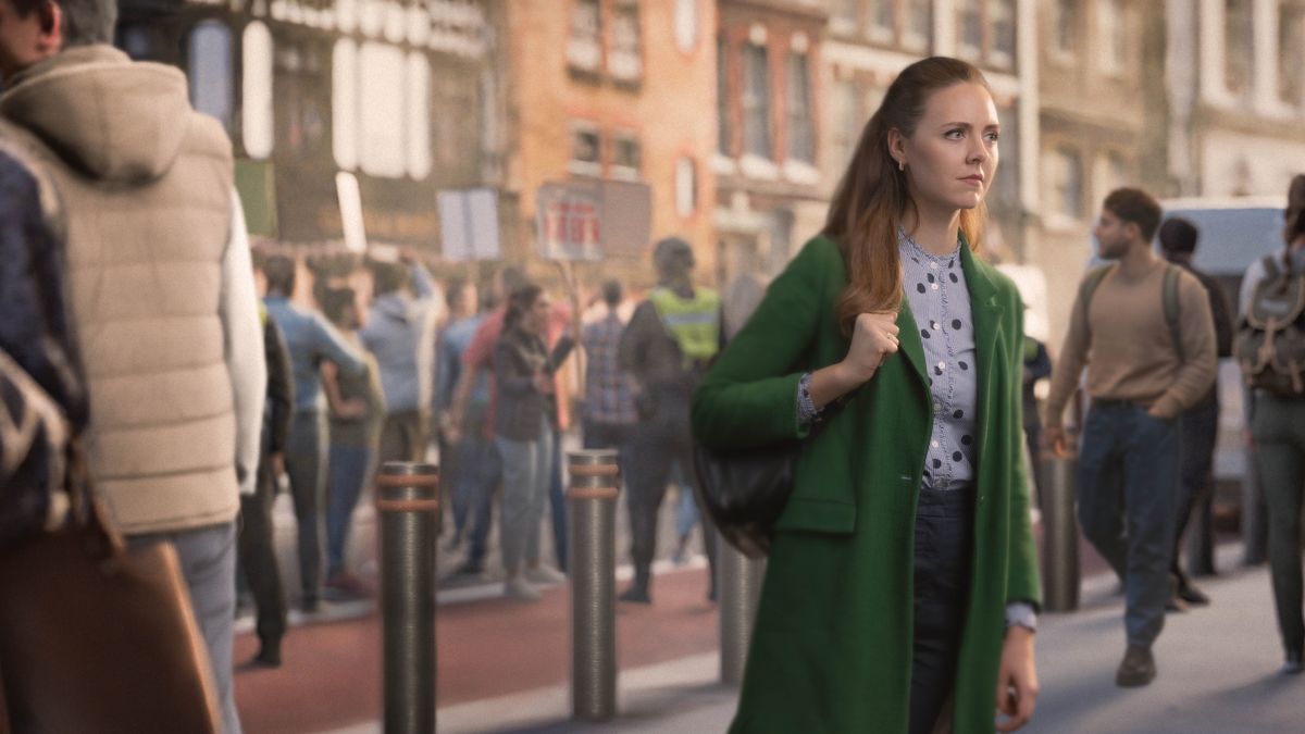 En una calle muy transitada, una hermana camina con calma mirando al frente mientras pasa de largo junto a una manifestación.