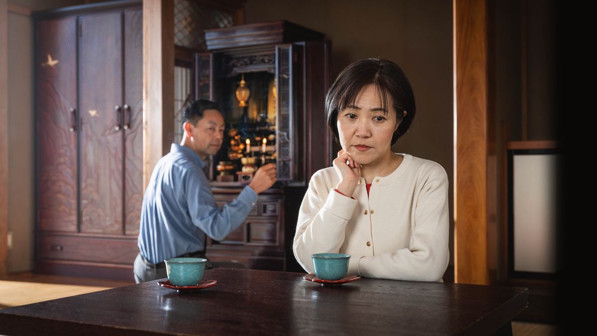 家里供着佛龛，丈夫在跪拜，姐妹若有所思。