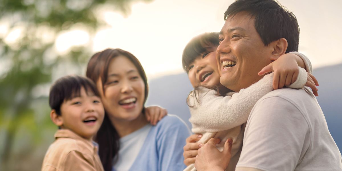 一家人在戶外玩，爸爸媽媽開心地摟著年幼的兒子和女兒。