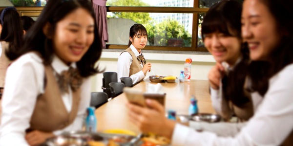一個女孩獨自坐在一旁看著其他女孩說說笑笑