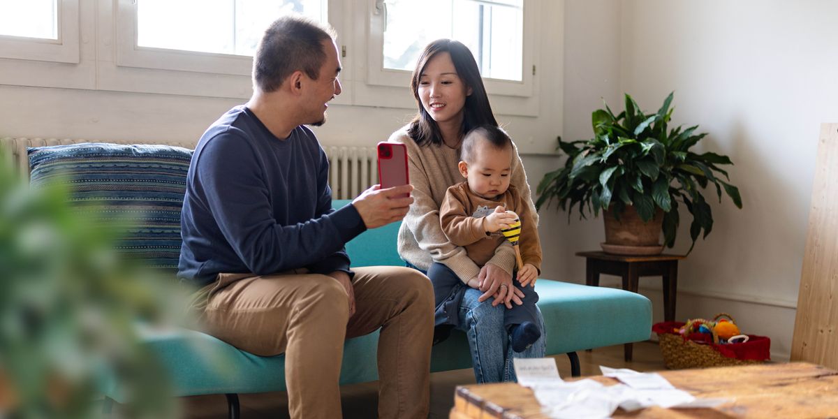 丈夫給妻子看手機，妻子抱著年幼的兒子。