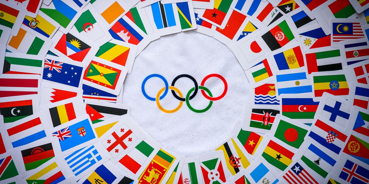 Olympijské kruhy, kolem kterých jsou vlajky mnoha národů.