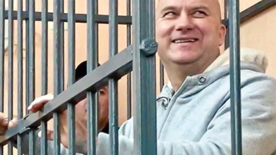 Bratr v soudní síni se drží za mříže a usmívá se