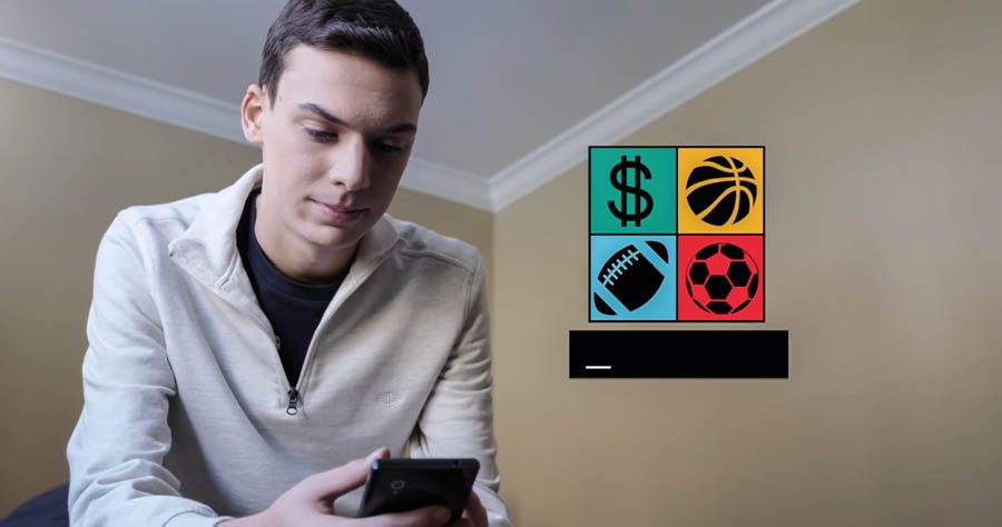 Scéna z videa „Nenapodobuj zrádce“. Mladý bratr si na mobilu prohlíží odkaz na sázení přes internet, který mu někdo poslal