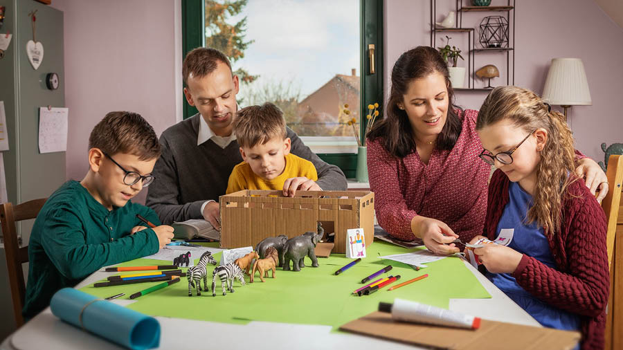 Rodiče vyrábějí se svými třemi dětmi model Noemovy archy a některá zvířata