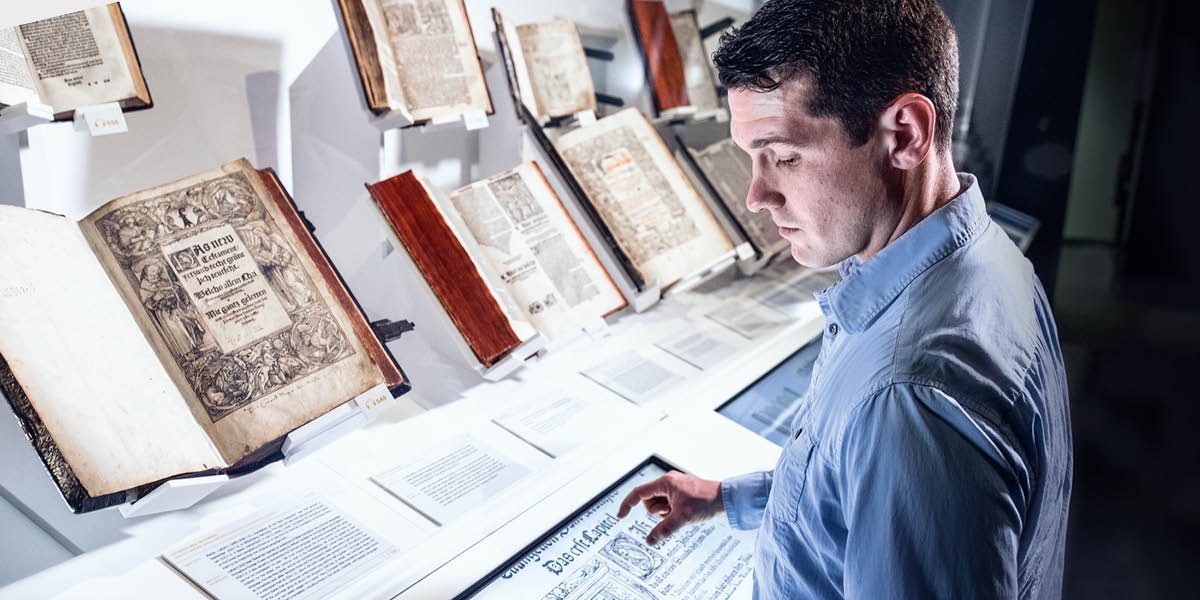 Un hombre mirando Biblias antiguas en un museo