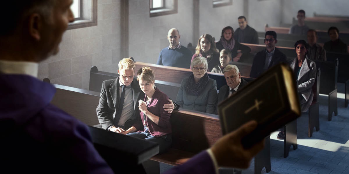 Un sacerdote sosteniendo una Biblia mientras dirige un sermón de funeral en una iglesia