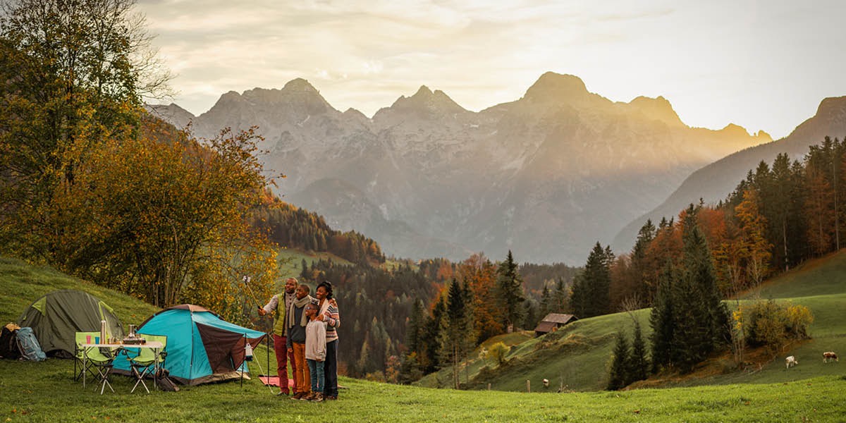 Una familia acampando en las montañas. Se están tomando una foto con las montañas detrás de ellos