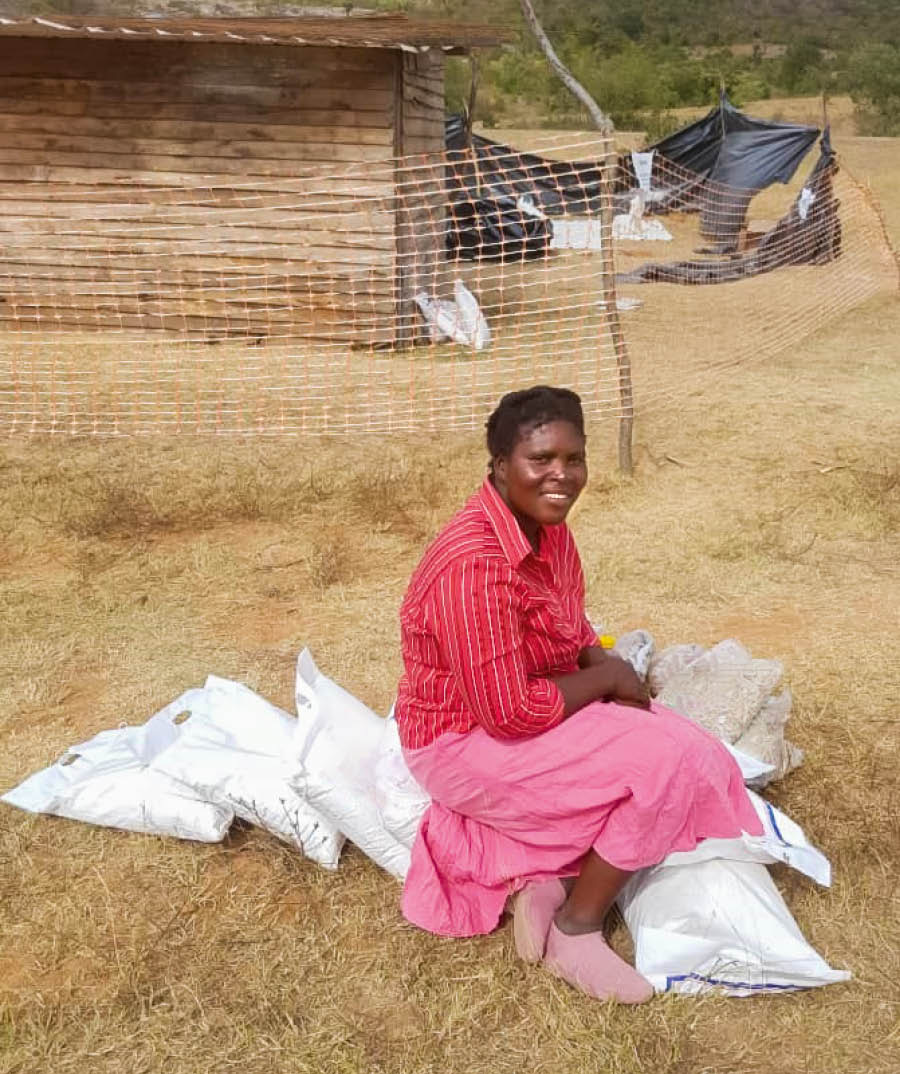Prisca frente a su casa, sonriendo con varias bolsas de comida.