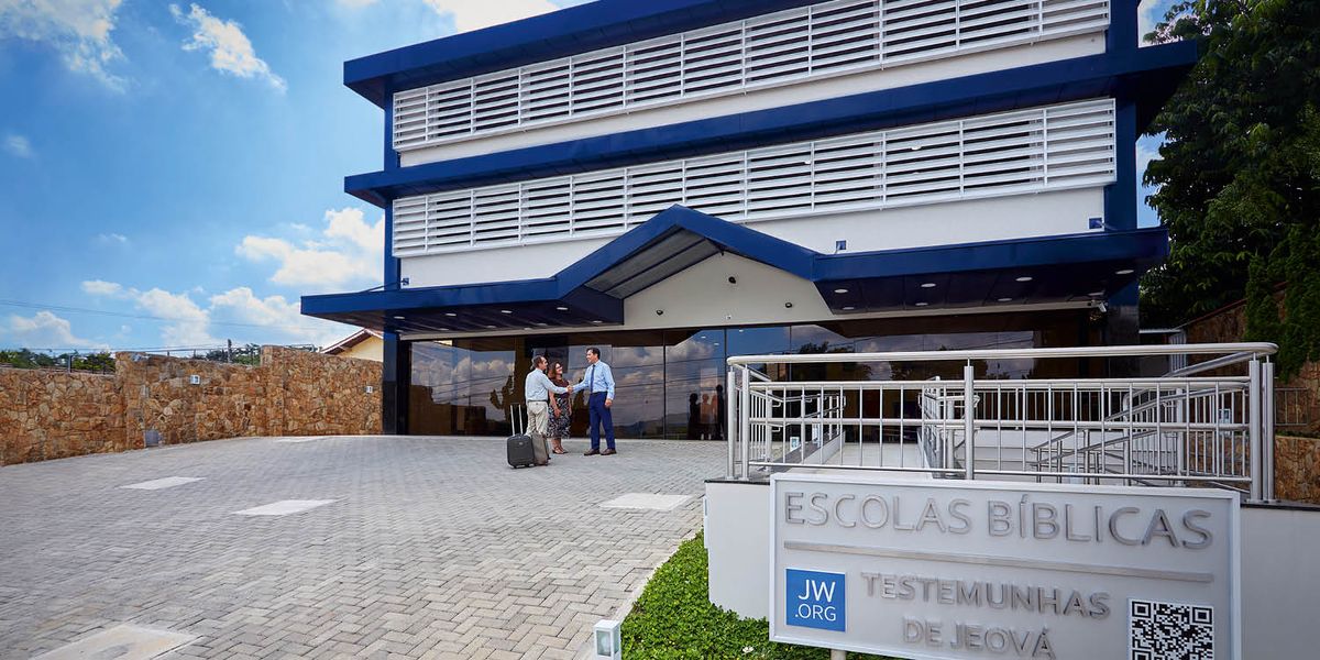 Un hermano dándoles una cálida bienvenida a unos hermanos a la entrada de las instalaciones de una escuela en Brasil.