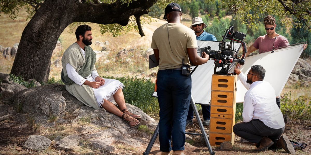 El equipo de rodaje se prepara para grabar en exteriores una escena de un episodio de “Las buenas noticias según Jesús”. El hermano que hace de Jesús está sentado bajo un árbol.