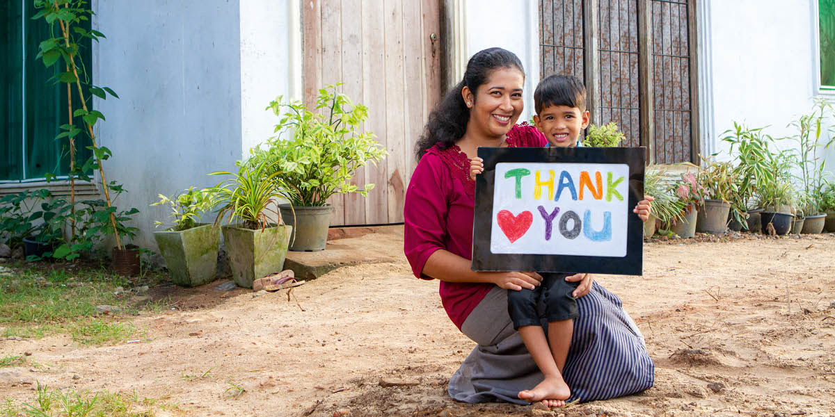 Imara y su hijo Enosh. Él tiene un cartel que dice “Gracias”.