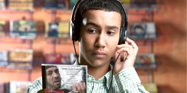 Un adolescente escucha música mientras revisa la carátula de un CD.