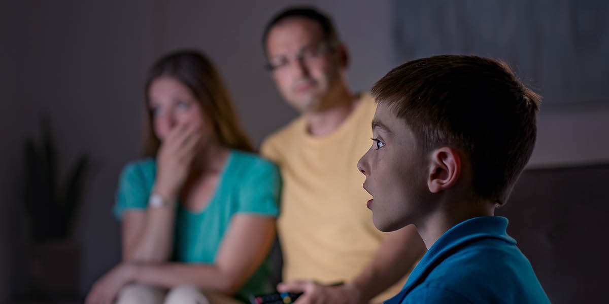 Una familia viendo la tele. El padre se da cuenta de que las noticias están afectando a su hijo.