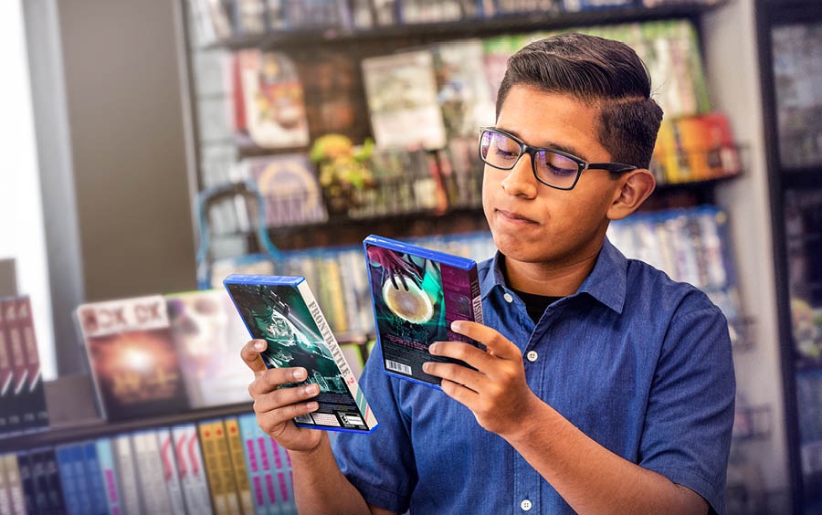 Un adolescente decidiendo qué videojuego va a comprar en una tienda de electrónica