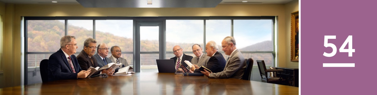 Lección 54. El Cuerpo Gobernante de los Testigos de Jehová en una sala de reuniones.