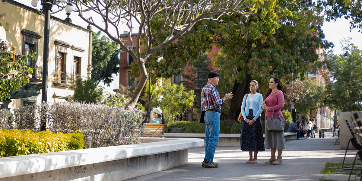 Un hombre habla con dos hermanas en un parque.