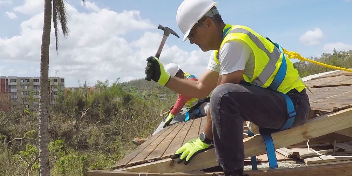 Unos hermanos en el Caribe reparando el tejado de una casa después de un huracán