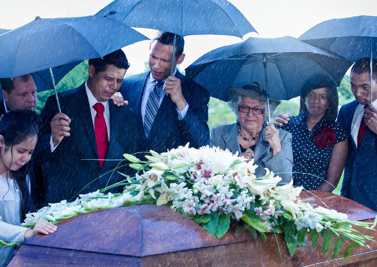 Una familia llorando junto a un ataúd adornado con flores