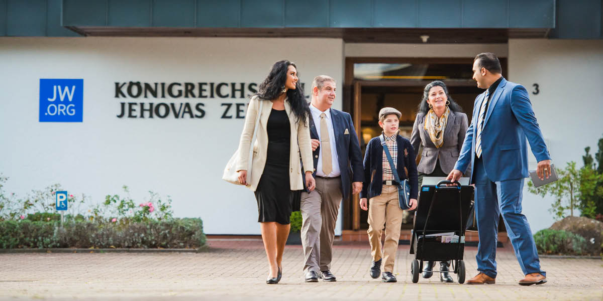 Un grupo de hermanos sale del Salón del Reino con un carrito de la predicación.