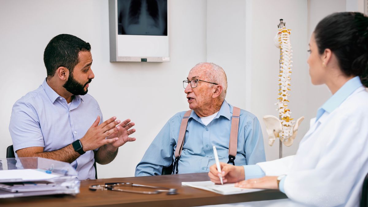 Un hermano joven le ayuda a un hermano mayor a hablar con su doctora.