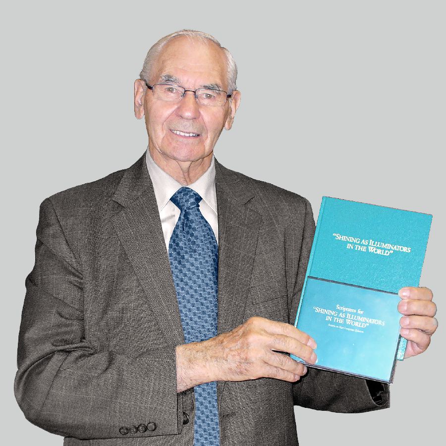Walter Markin, a los 79 años, sosteniendo el libro de texto de la Escuela del Servicio de Precursor y el DVD en lenguaje de señas