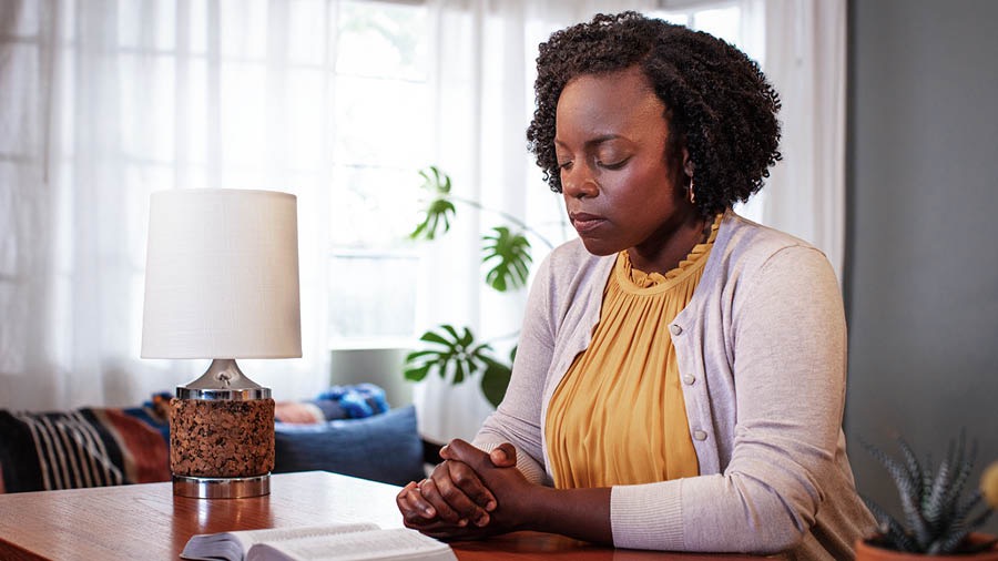 Una hermana ora con la Biblia abierta sobre la mesa.