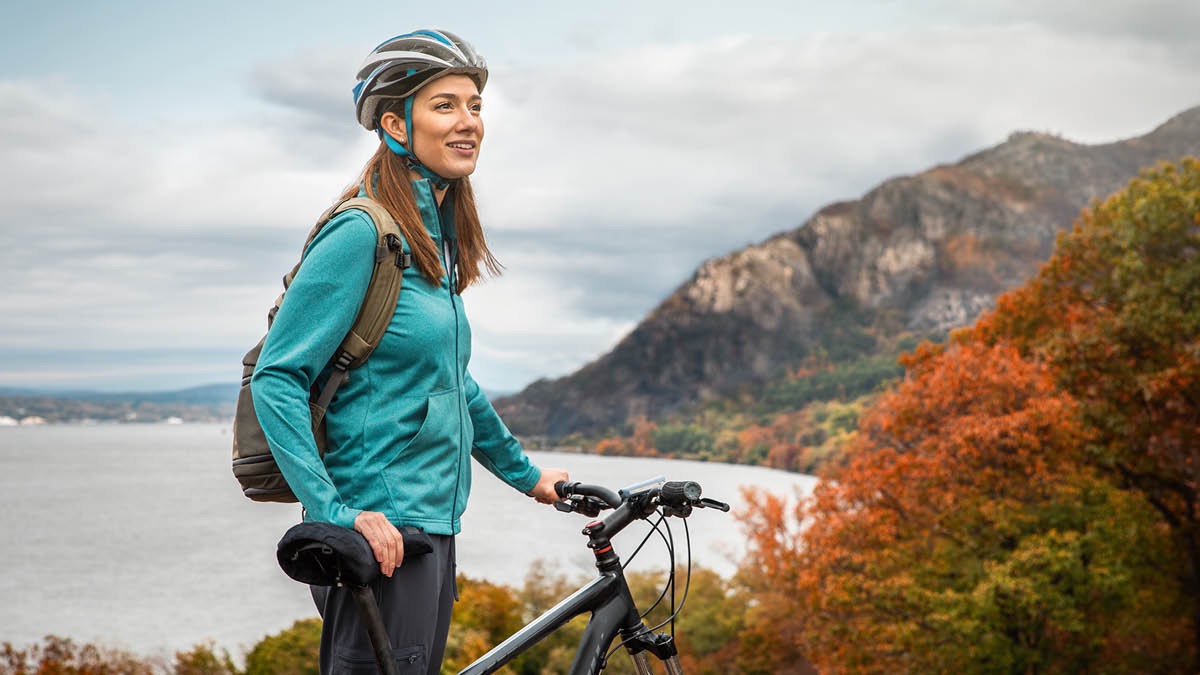 Una hermana se detiene con su bicicleta en una colina junto a un lago para disfrutar de la creación.