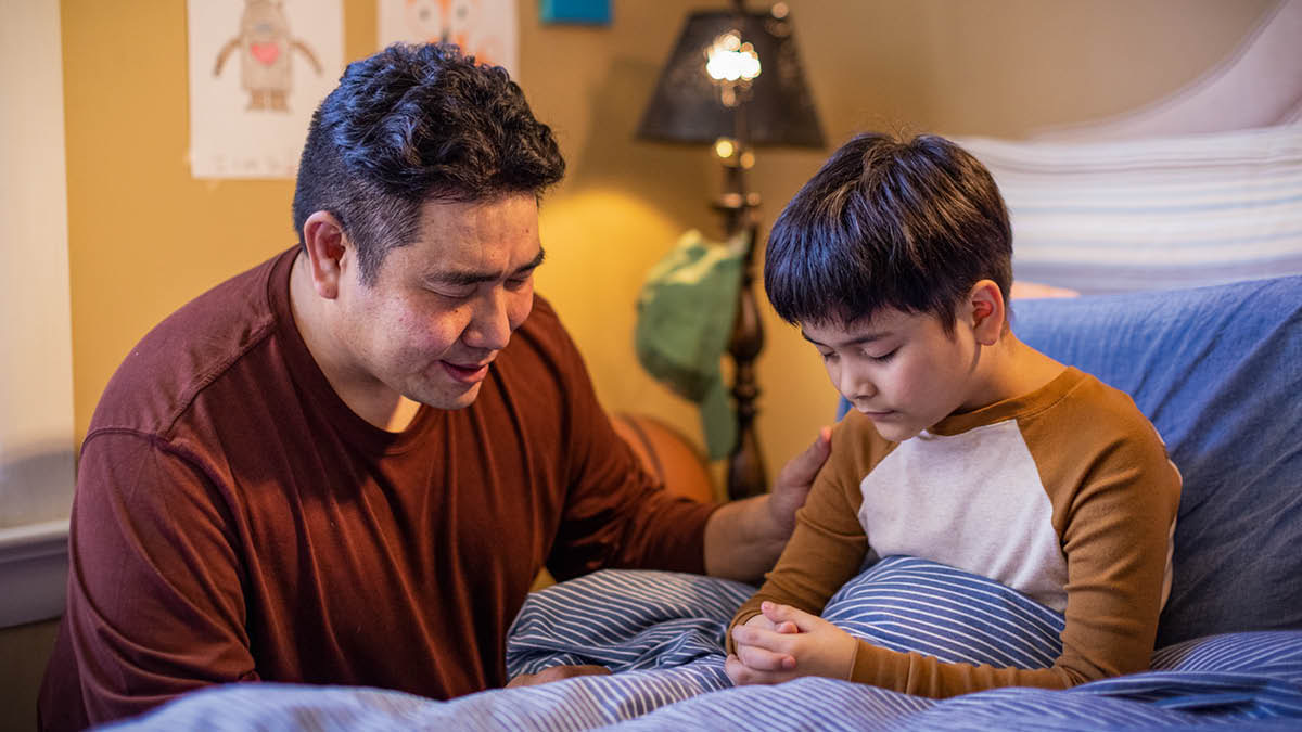 Un padre ora con su hijito antes de irse a dormir.
