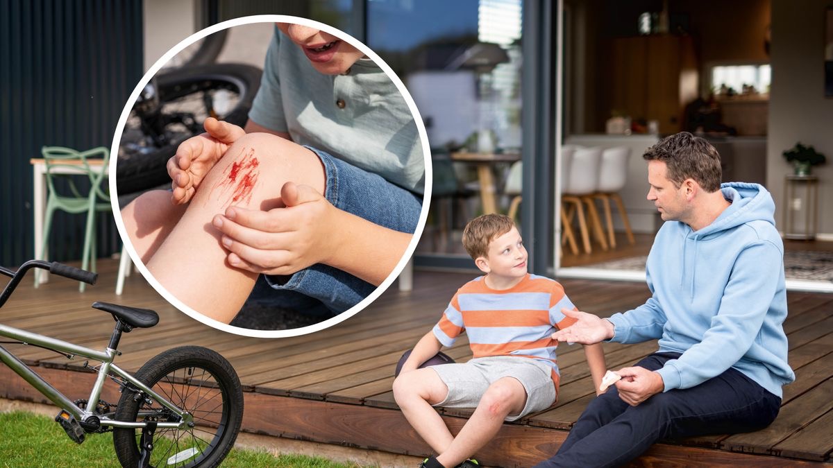 Un padre está hablando con su hijo mientras sostiene una curita o tirita. La vista ampliada de la rodilla del niño muestra que se raspó.