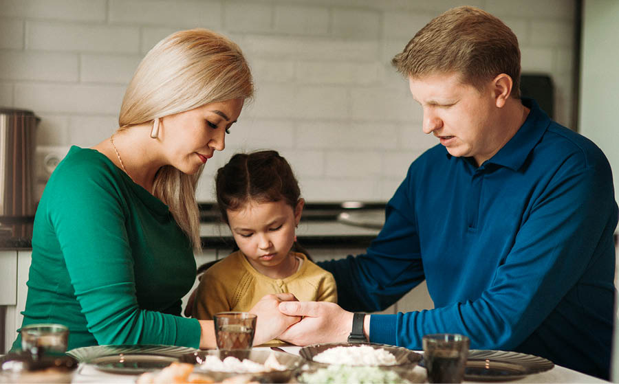 Una familia orando antes de comer.