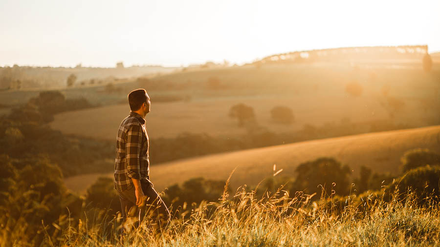 Un hombre caminando por el campo mientras se pone el sol.