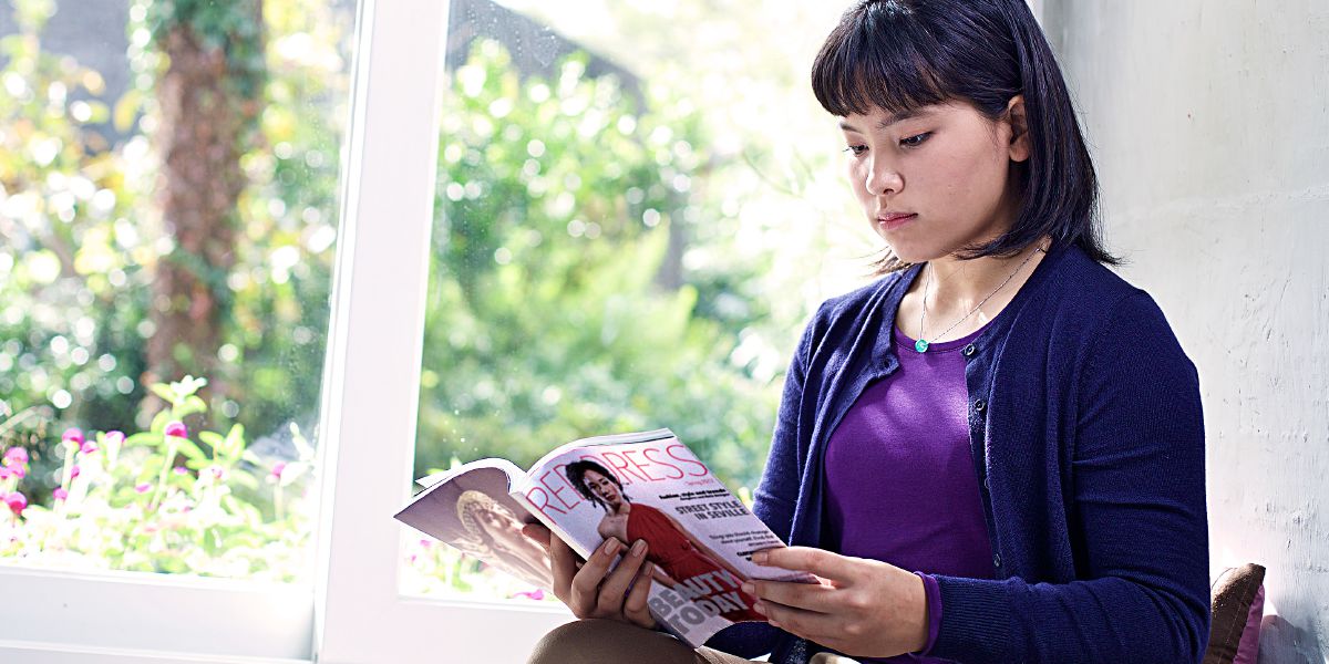 Una adolescente mirando una revista de moda