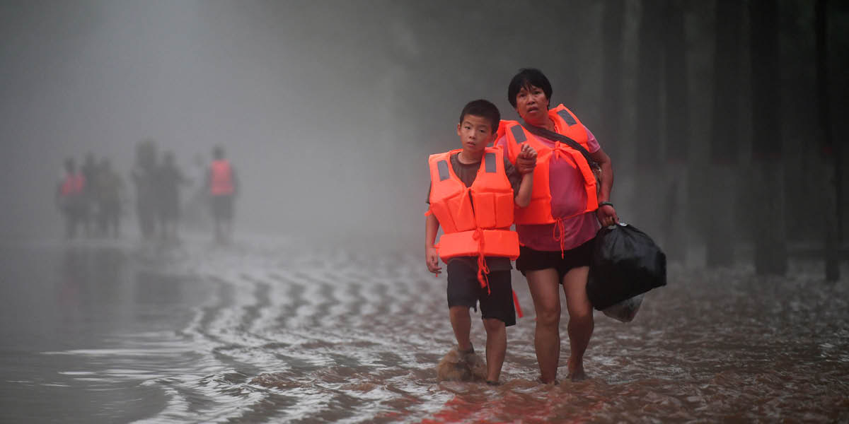 Una mujer y un niño caminando por una carretera inundada.