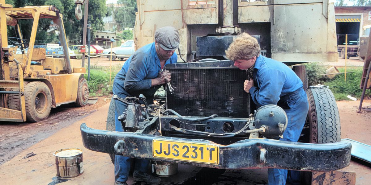 Ein weißer und ein schwarzer Bruder reparieren gemeinsam ein Fahrzeug.