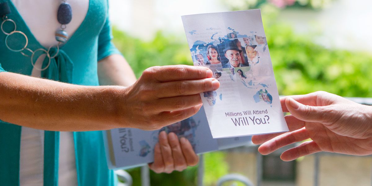 Eine Zeugin Jehovas überreicht jemandem eine Einladung zum Abendmahl