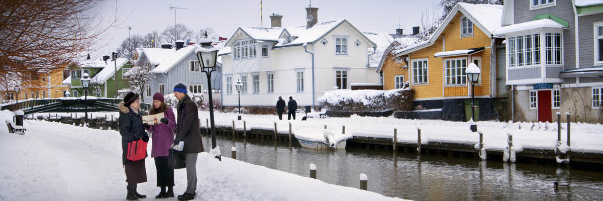 F. Twee Getuigen van Jehovah in Zweden prediken in de sneeuw tot een vrouw langs een kanaal.